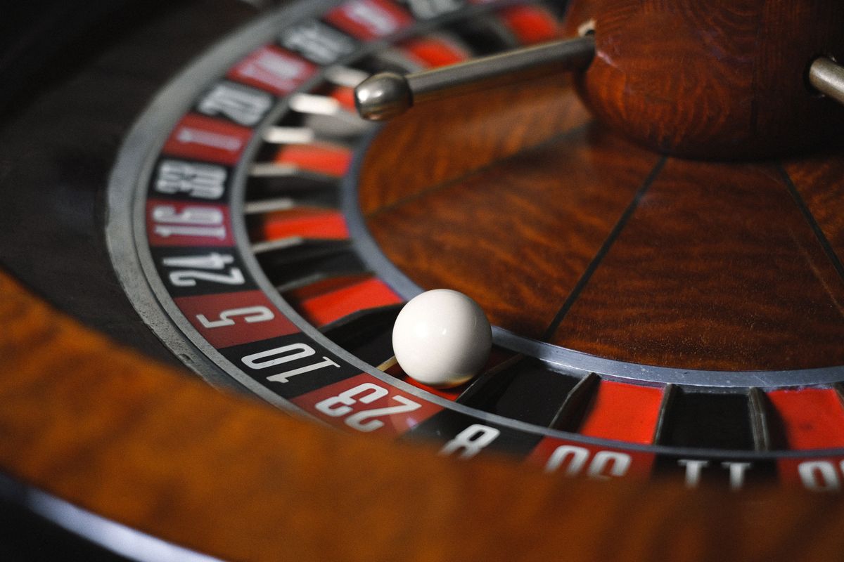 Roda roulette dengan bola putih di atas jalur angka merah dan hitam